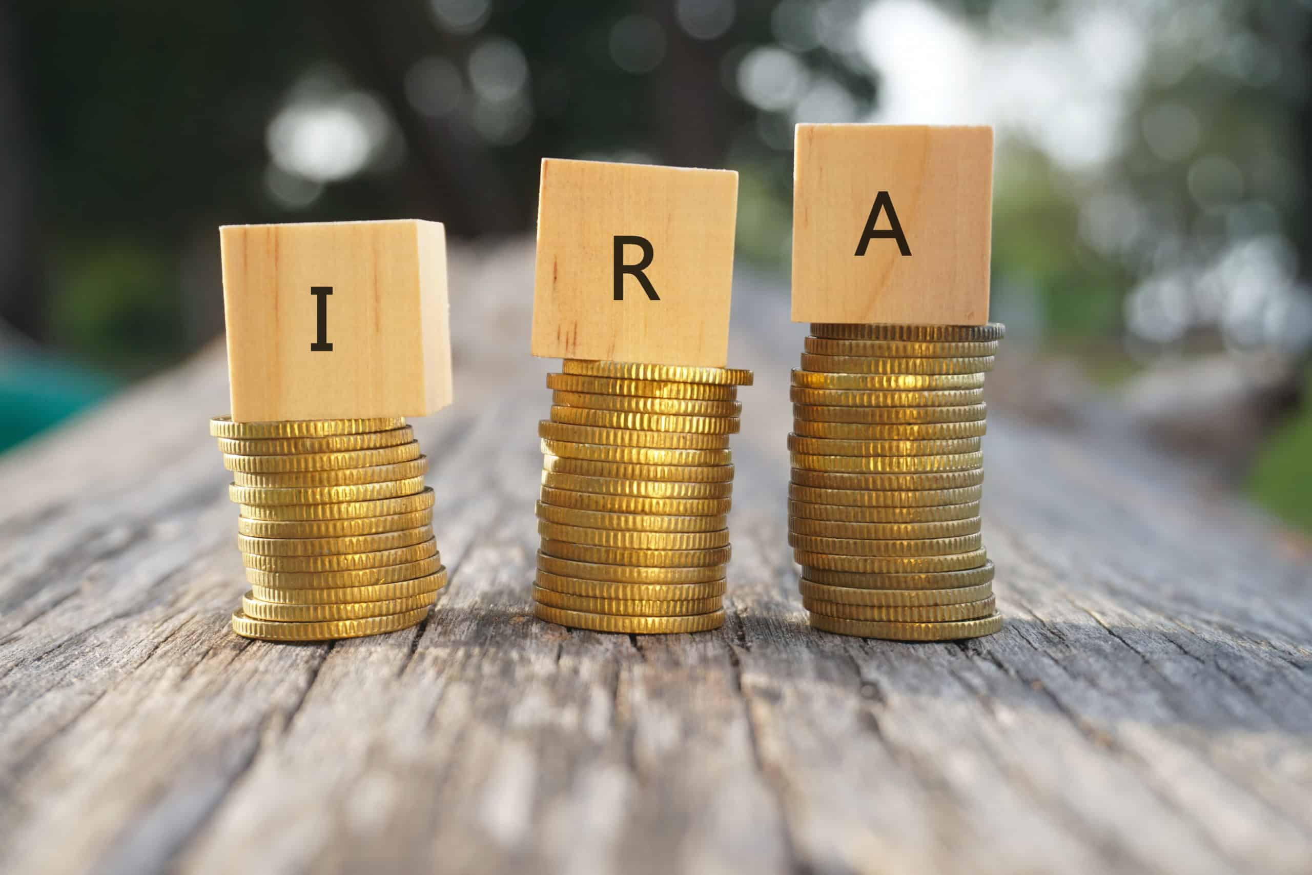 Close up of stacking gold coins and wooden blocks written IRA on nature background and natural lighting. Individual Retirement Account concept